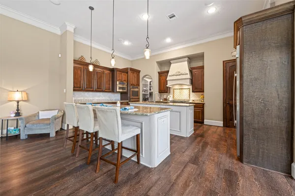a kitchen with stainless steel appliances kitchen island granite countertop a refrigerator a stove a sink and a dining table with wooden floor