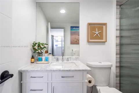 a bathroom with a granite countertop sink a toilet and mirror