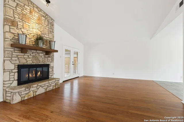 a view of an empty room with wooden floor fireplace and a window
