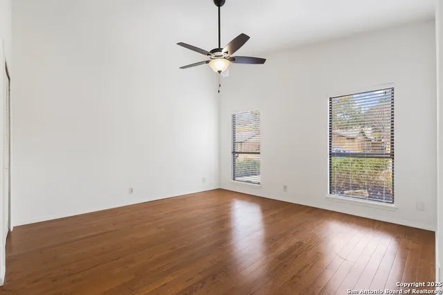 an empty room with wooden floor window and ceiling fan
