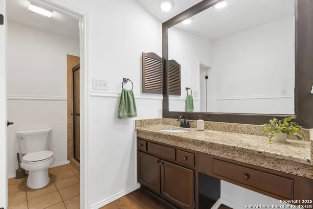 a bathroom with a granite countertop sink and a toilet