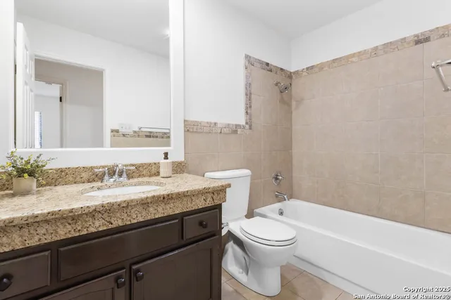 a bathroom with a granite countertop bathtub sink vanity mirror and toilet