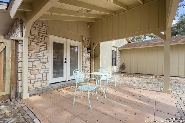 a patio with a table and chairs and potted plants