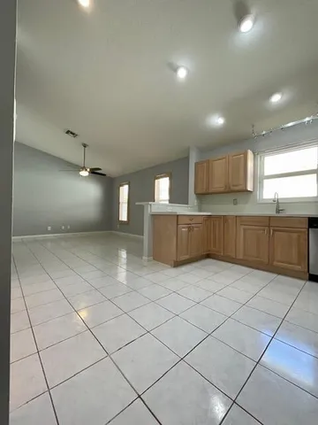an empty room with chandelier fan and windows