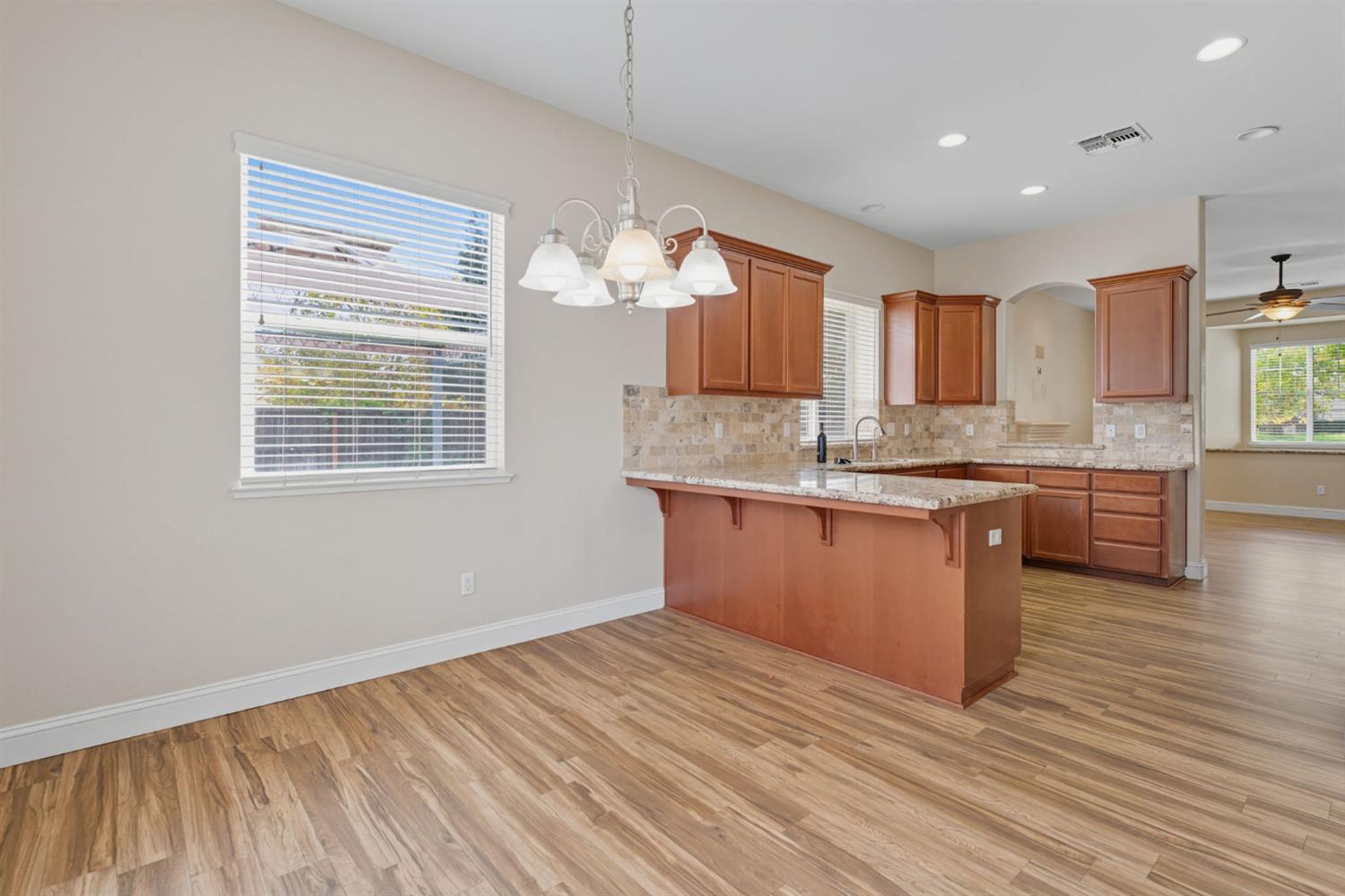 433 Travertine Drive Ripon, CA 95366 - Photo 17 of 38 a kitchen with granite countertop wooden floors and wide window