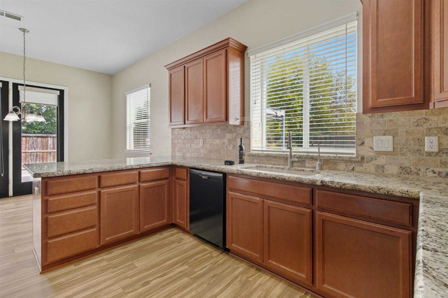 433 Travertine Drive Ripon, CA 95366 - Photo 10 of 38 a kitchen with granite countertop wooden cabinets a sink and a window