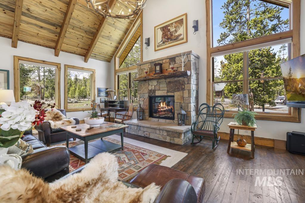 65 Goat Creek Way Stanley, ID 83278 - Photo 8 of 32 Living area featuring a stone-clad fireplace, vaulted wood-finish ceiling, wood-frame windows, and wood-finish flooring