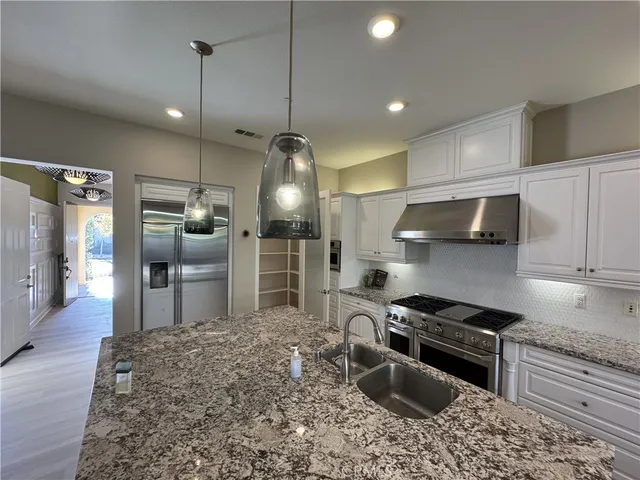 a kitchen with stainless steel appliances granite countertop a sink stove a refrigerator and a granite counter tops