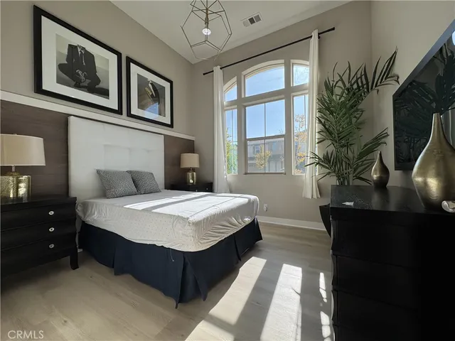 a spacious bedroom with a bed and a potted plant on the dresser