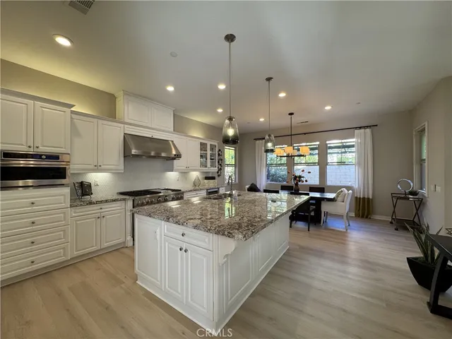 a large kitchen with stainless steel appliances granite countertop a lot of counter space and wooden floors