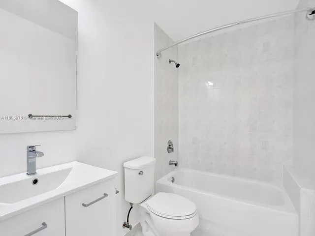 a bathroom with a bathtub shower sink vanity and toilet