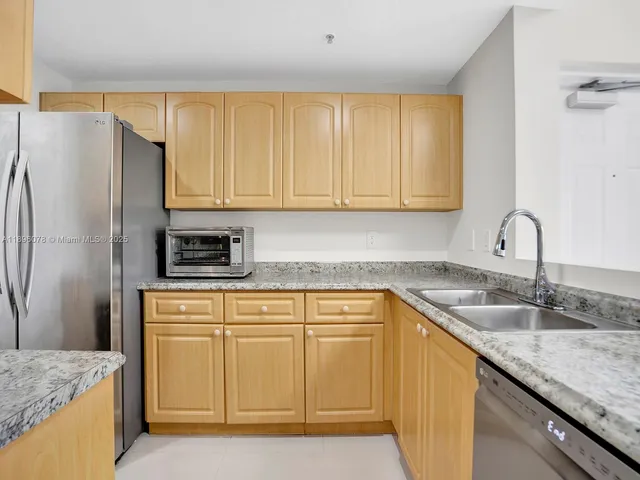 a kitchen with granite countertop a sink a refrigerator and cabinets