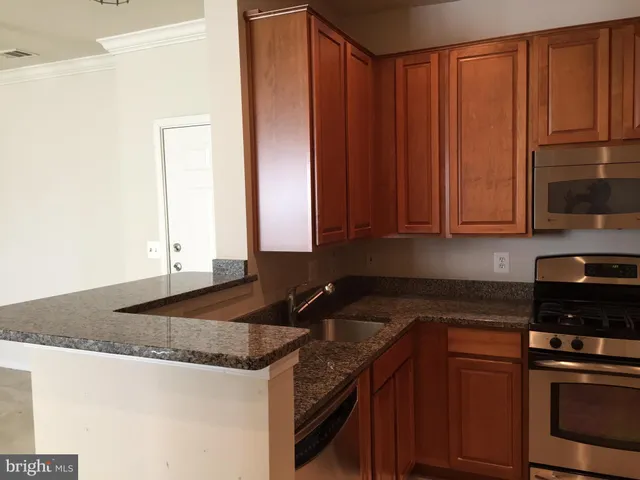 a kitchen with granite countertop stainless steel appliances a sink a stove a microwave and cabinets