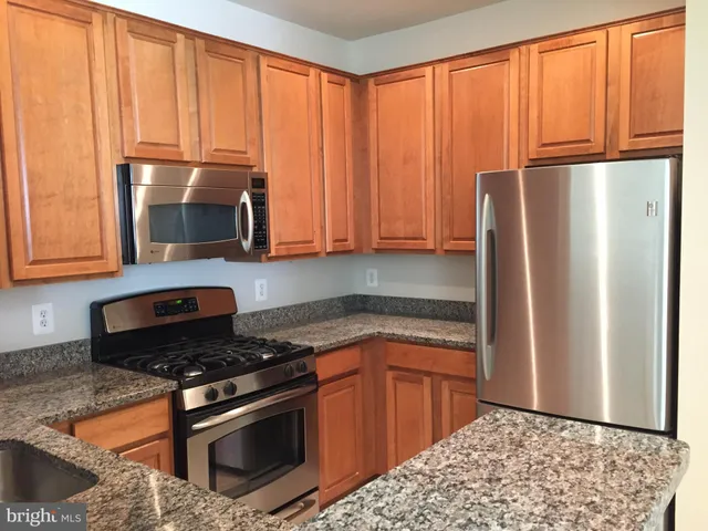 a kitchen with stainless steel appliances granite countertop a refrigerator stove and microwave