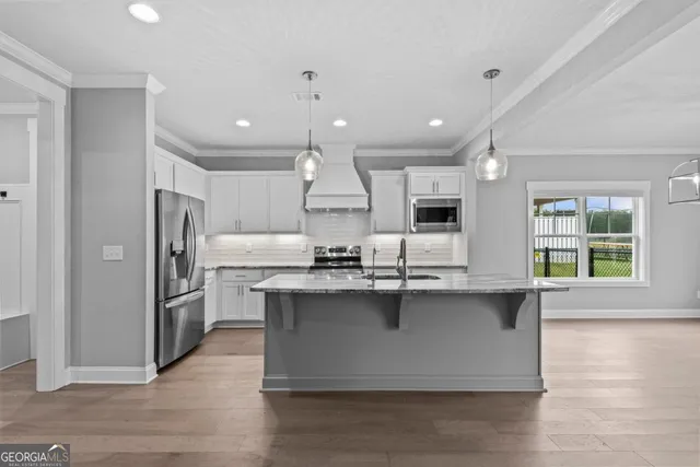 a large kitchen with stainless steel appliances a large counter top a stove and a refrigerator