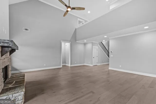 an empty room with wooden floor ceiling fan and windows