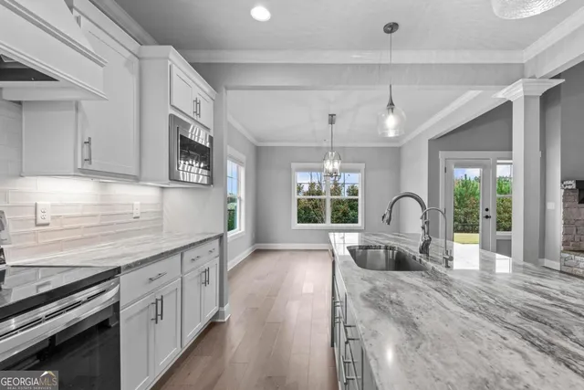 a large kitchen with stainless steel appliances granite countertop a lot of counter space and wooden floors