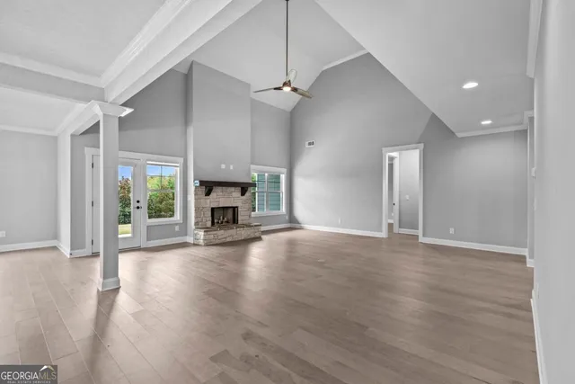 an empty room with wooden floor fireplace and windows