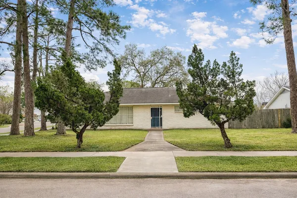 a front view of a house with a yard and large trees