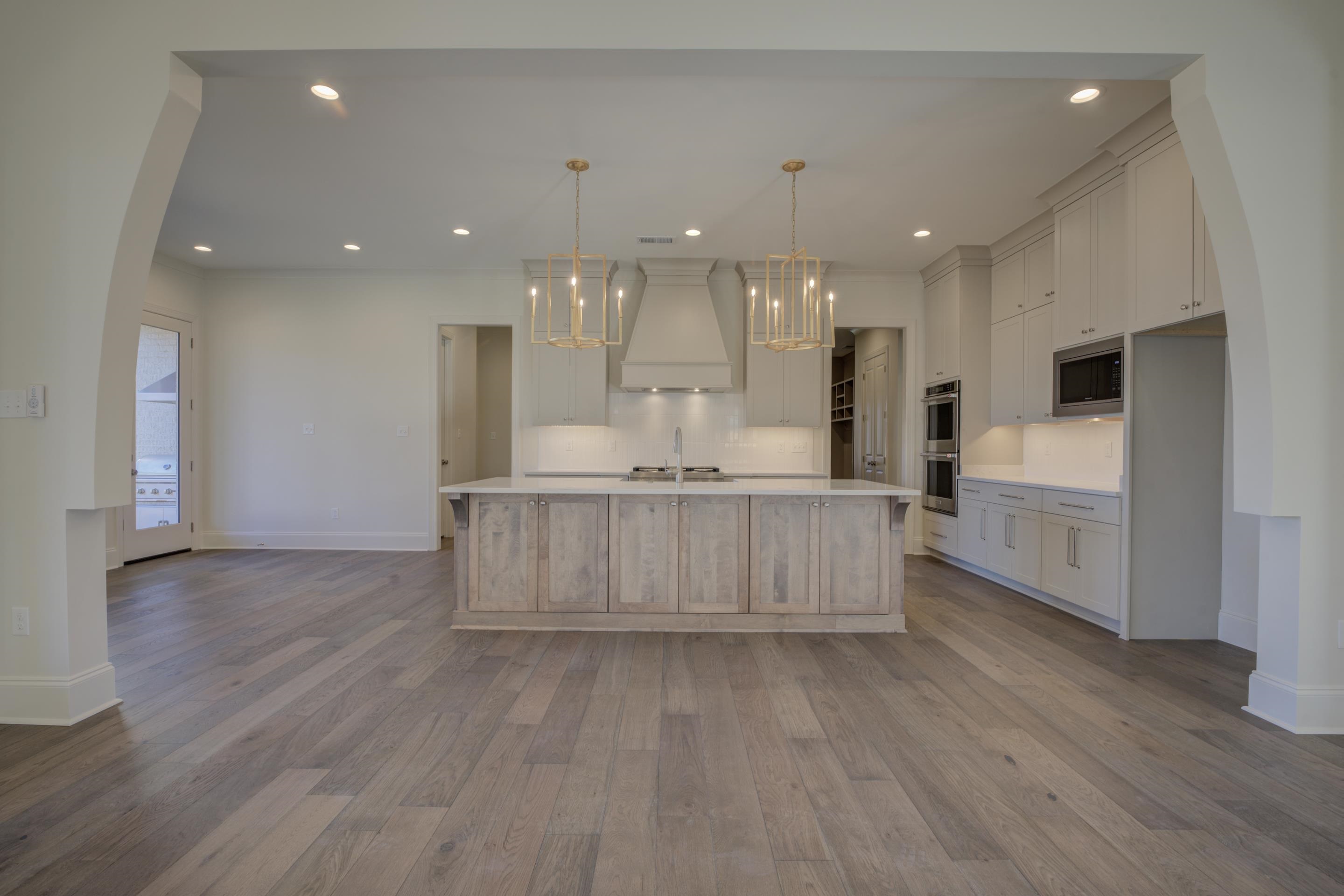 3329 Bailey Station Road Collierville, TN 38017 - Photo 11 of 31 Kitchen with a large island, decorative light fixtures, appliances with stainless steel finishes, custom range hood, and light wood-type flooring