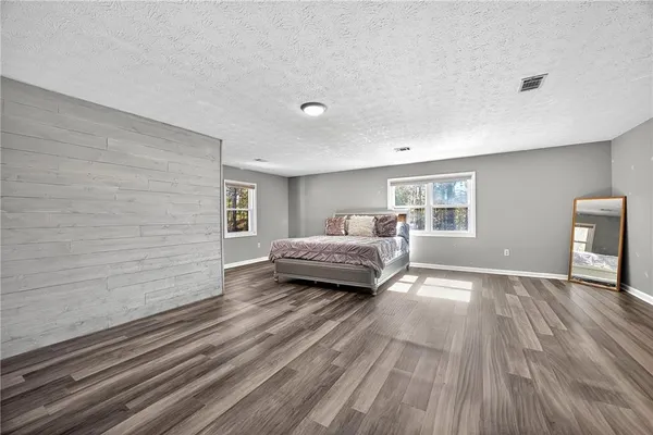a spacious bedroom with a bed and wooden floor