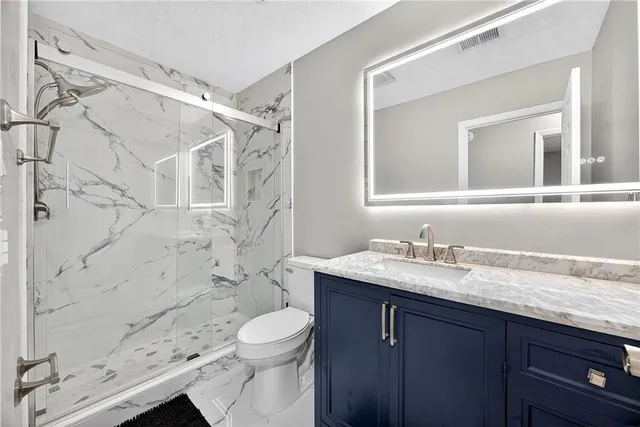 a bathroom with a granite countertop sink a toilet and shower