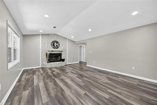 a view of empty room with wooden floor and fireplace