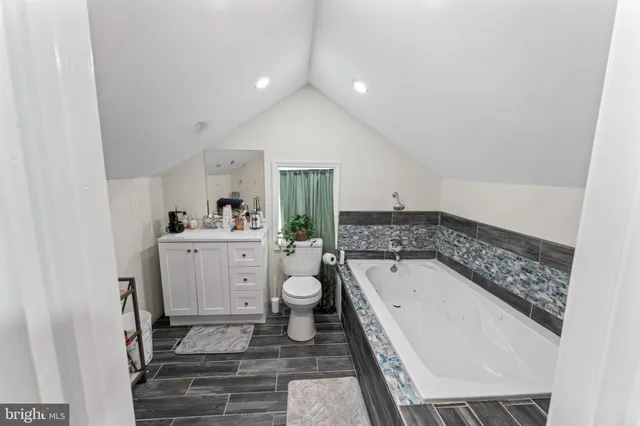 a bathroom with a granite countertop sink mirror vanity and bathtub
