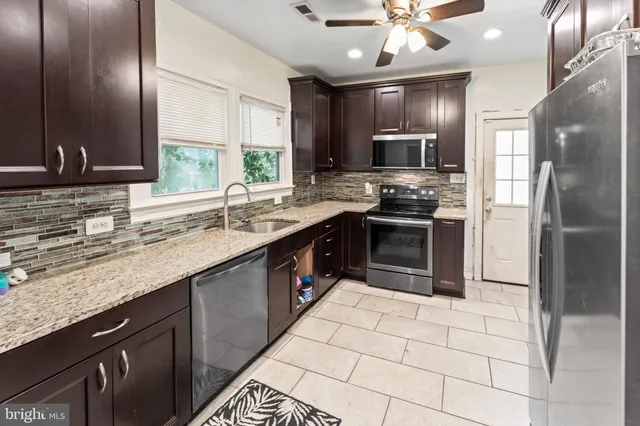 a kitchen with stainless steel appliances granite countertop a sink stove and refrigerator