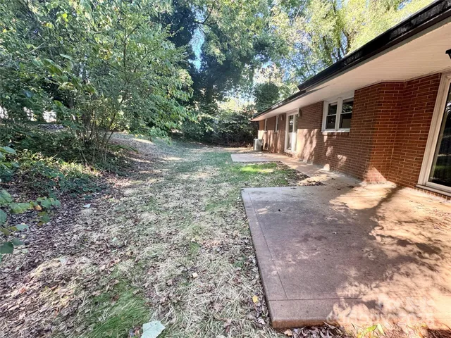 a backyard of a house with large trees and wooden fence