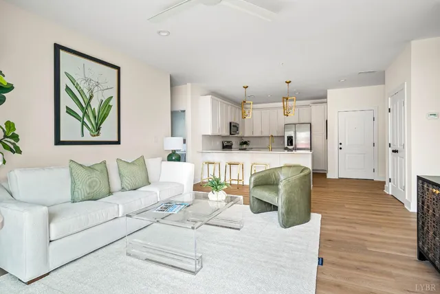 a living room with stainless steel appliances kitchen island granite countertop furniture and a wooden floor