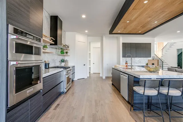 a large kitchen with stainless steel appliances a large counter top a stove and a sink