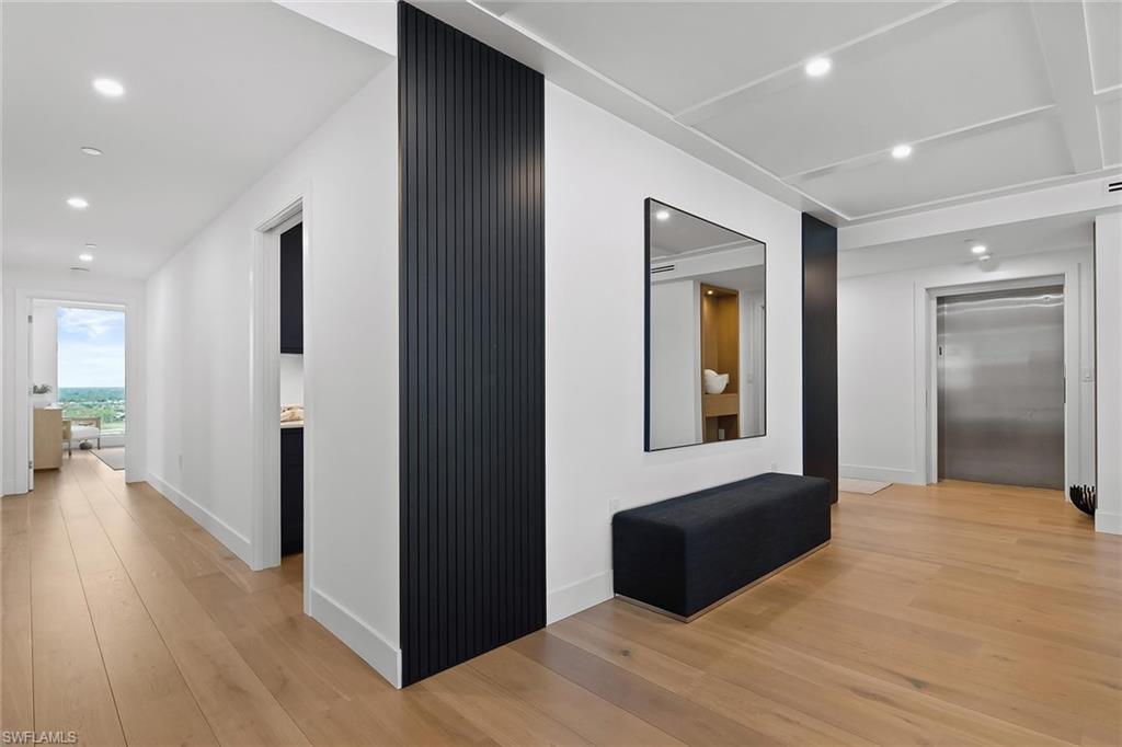 13935 Old Coast Road, Unit 2206 Naples, FL 34110 - Photo 15 of 50 Private elevator entry featuring a striking wood accent wall and two hallways leading to guest suites laundry/office and den