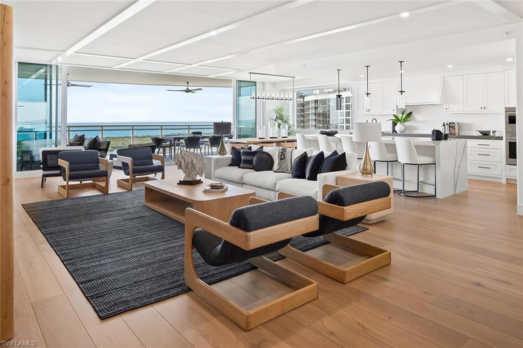 13935 Old Coast Road, Unit 2206 Naples, FL 34110 - Photo 3 of 50 Furnished 22nd-floor great room with expansive big-water views, featuring impact-rated pocketing doors that open wide to the terrace for seamless indoor-outdoor living