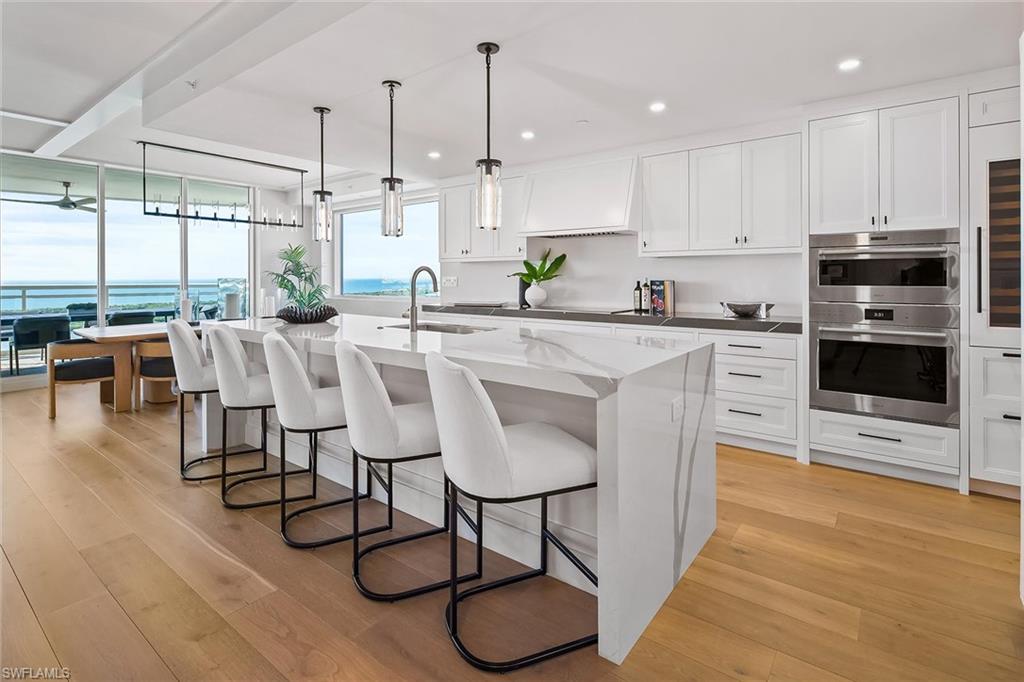 13935 Old Coast Road, Unit 2206 Naples, FL 34110 - Photo 4 of 50 The chef's kitchen features Wolf and Sub-Zero appliances, quartz countertops, oversized island, wine cooler, refrigerator and freezer drawers, with water views just beyond