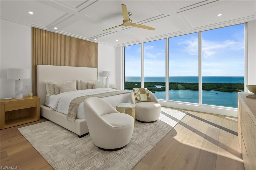 13935 Old Coast Road, Unit 2206 Naples, FL 34110 - Photo 9 of 50 Furnished king-size primary bedroom with a wall of windows framing breathtaking Gulf and bay views
