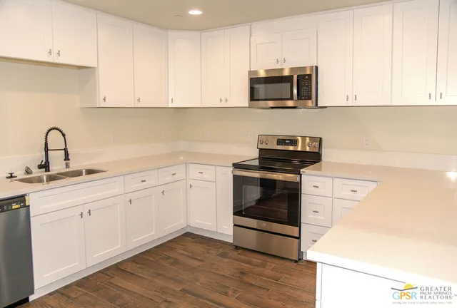 a kitchen with granite countertop white cabinets and stainless steel appliances