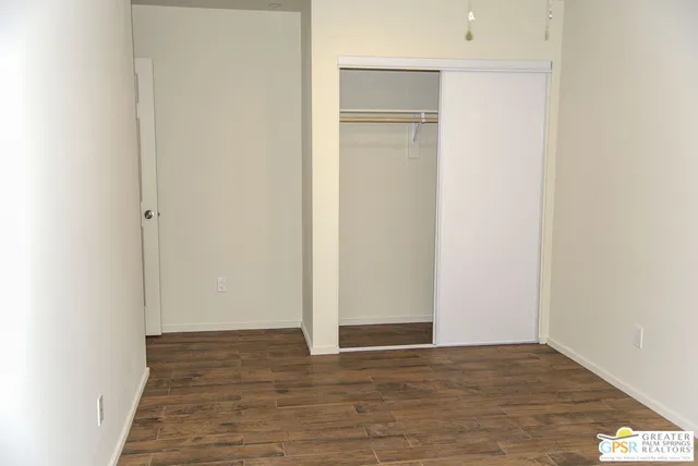 a view of an empty room with wooden floor and closet