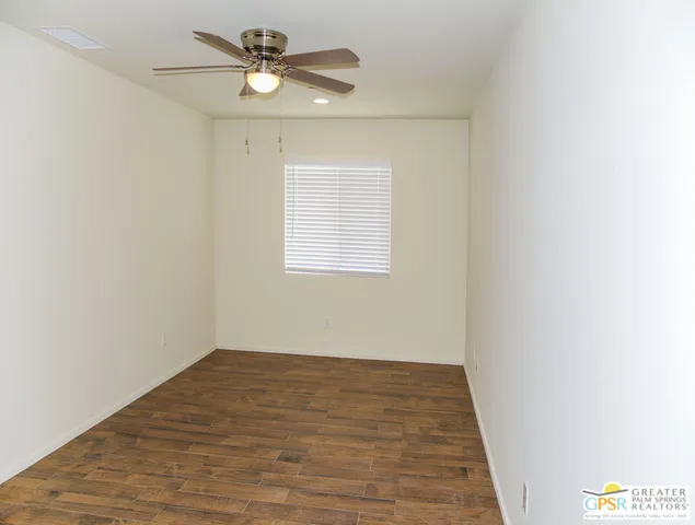 an empty room with a window and a ceiling fan