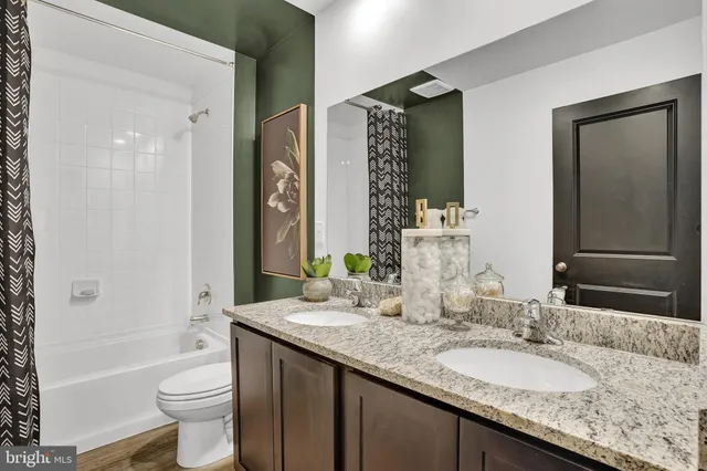 a bathroom with a granite countertop toilet a sink and a large mirror