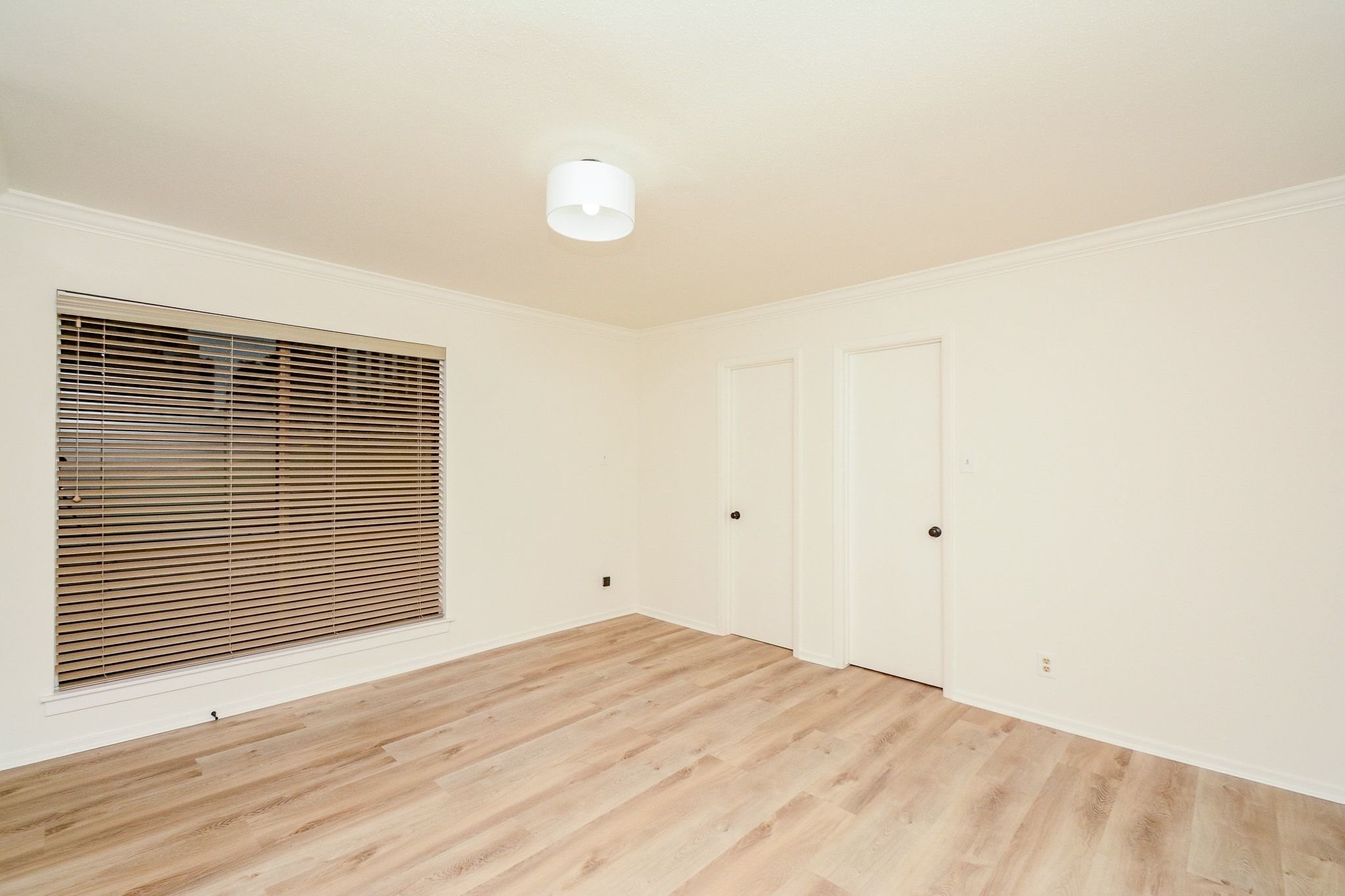 820 Harold Street Houston, TX 77006 - Photo 26 of 33 A bright, well-sized secondary bedroom with fresh LVP flooring, crown molding, and wood blinds on the oversized window.