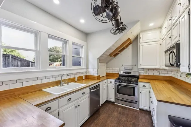 a kitchen with stainless steel appliances granite countertop a sink a stove and a wooden floors