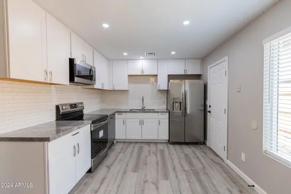 a kitchen with stainless steel appliances granite countertop a stove a sink and a refrigerator