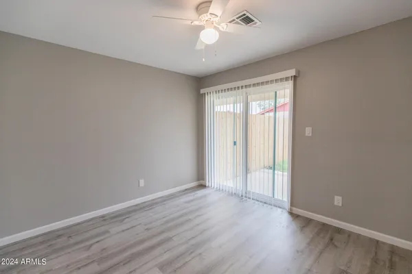 a view of an empty room with wooden floor and a ceiling fan