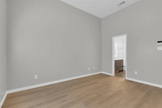 an empty room with wooden floor and bathroom