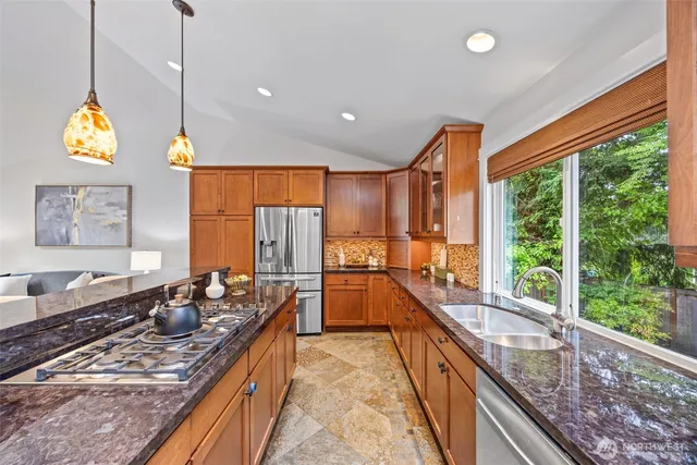a kitchen with stainless steel appliances granite countertop sink stove and wooden cabinets
