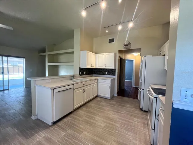 a kitchen with granite countertop a refrigerator and wooden floor