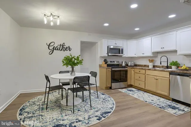 a kitchen with wooden floors stainless steel appliances and white cabinets