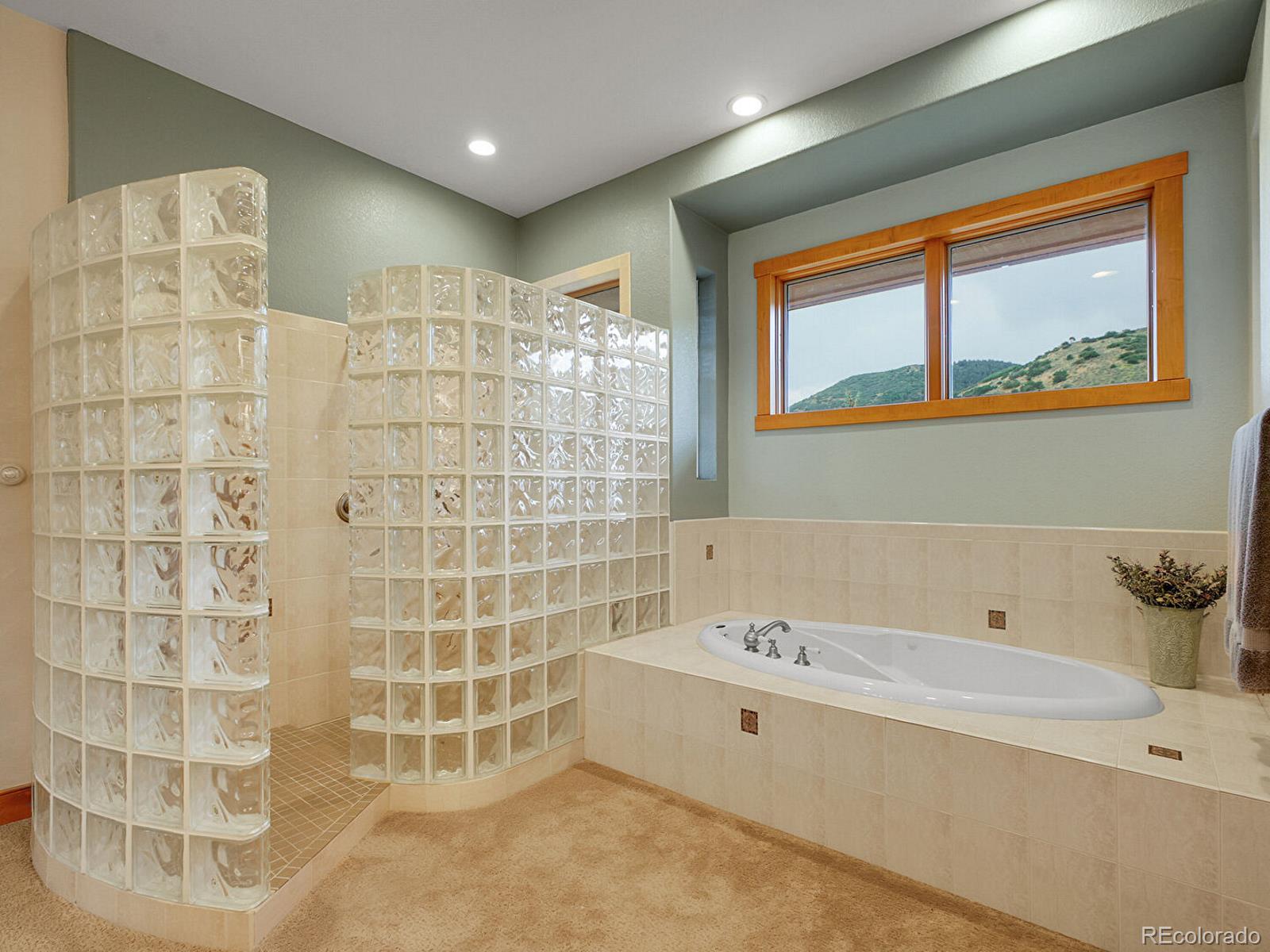 16285 Sandstone Drive Morrison, CO 80465 - Photo 22 of 47 a bathroom with a bathtub and a shower