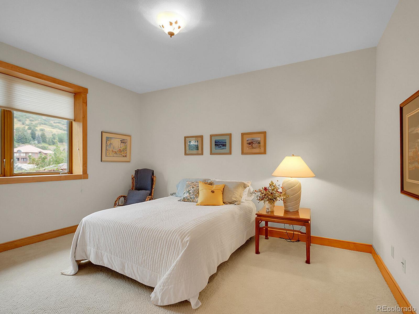 16285 Sandstone Drive Morrison, CO 80465 - Photo 36 of 47 a bedroom with a bed and a lamp on dresser
